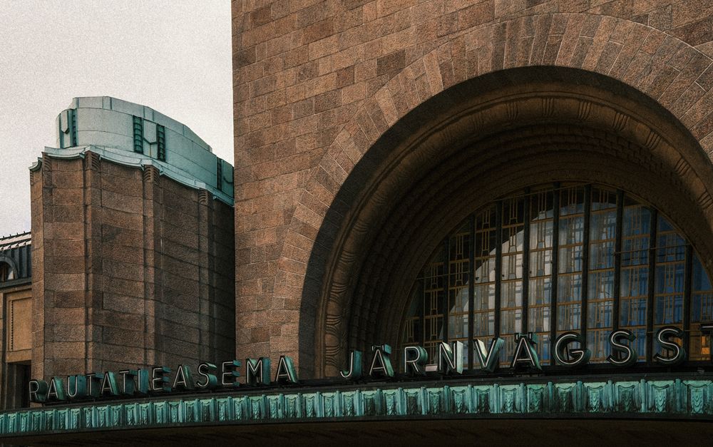 Historic Helsinki Central Railway Station facade with copper lettering and grand stone arch architecture.