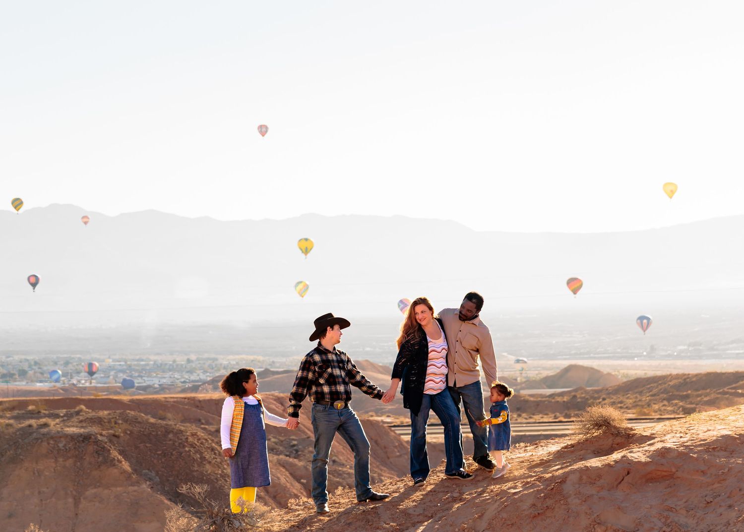 Large family portrait in coordinating teal and white outfits posed against a scenic red rock canyon backdrop.
