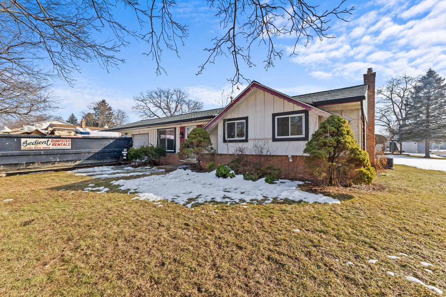 Ranch-style home with brick accents, manicured shrubs, and snow-dusted lawn in winter.