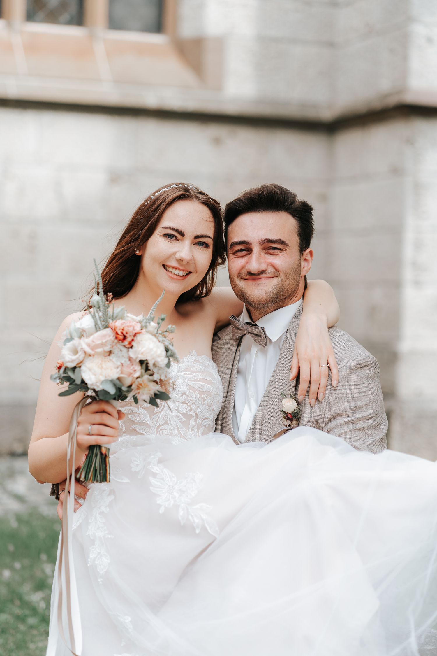 A beautiful wedding portrait of a couple posing together with the bride holding a delicate floral bouquet.