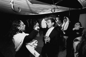 Black and white photo of people dancing and socializing at a formal evening party or wedding reception.