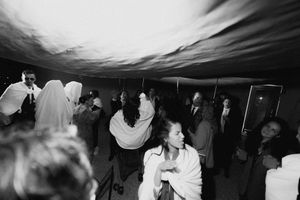 Black and white photo of elegantly dressed guests dancing and socializing under a tent at a formal evening event.