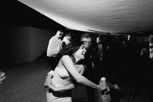 Black and white photo of people dancing and socializing at a lively indoor party event.