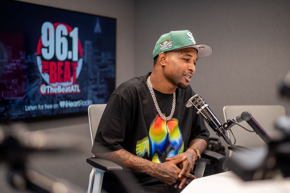 Man in green cap and chain necklace speaking into microphone at 96.1 The Beat radio station Atlanta.