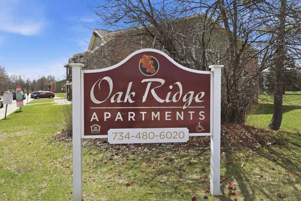 Oak Ridge Apartments entrance sign with phone number 734-480-6020 on a sunny day.
