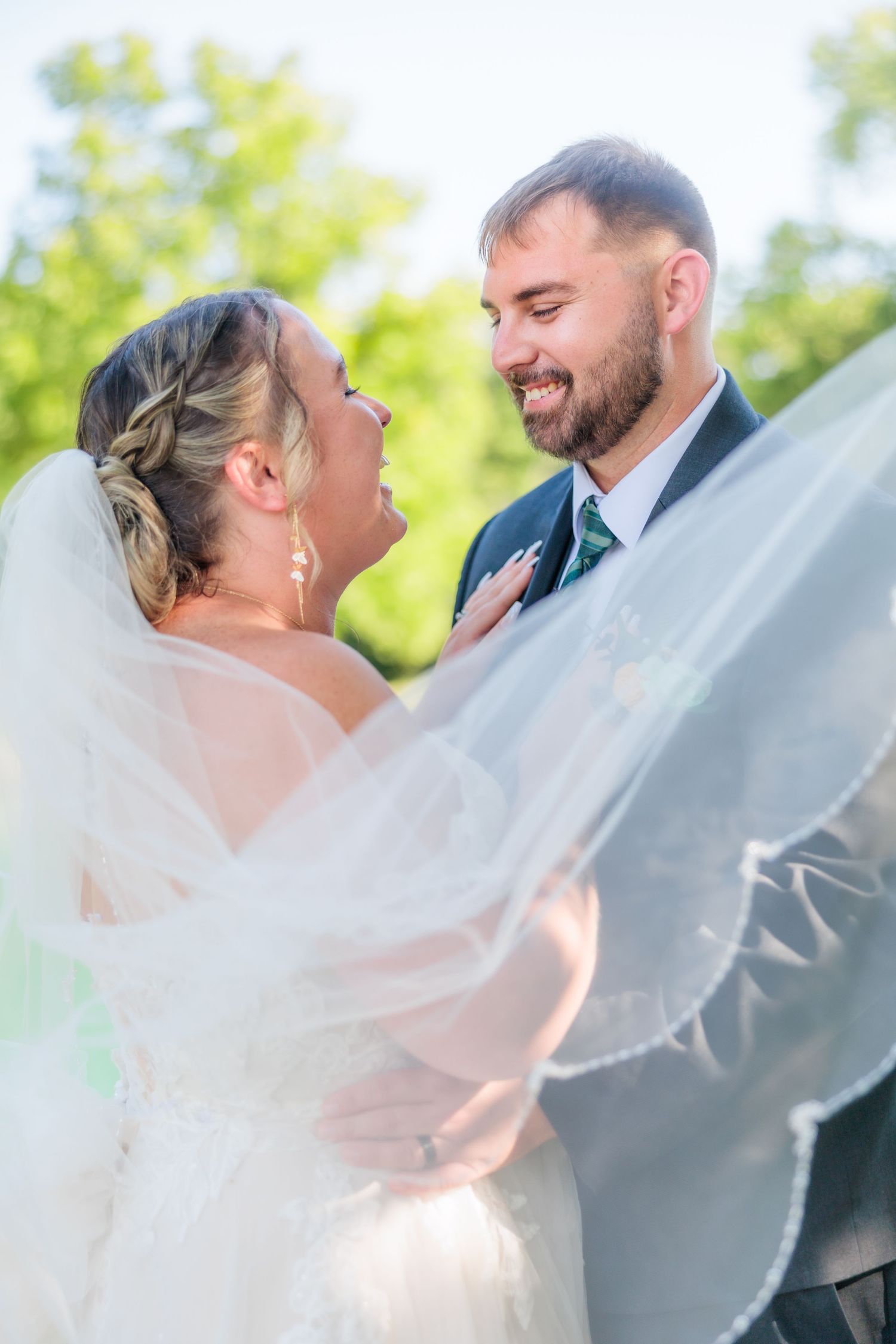 Joyful wedding couple sharing intimate moment with flowing veil.