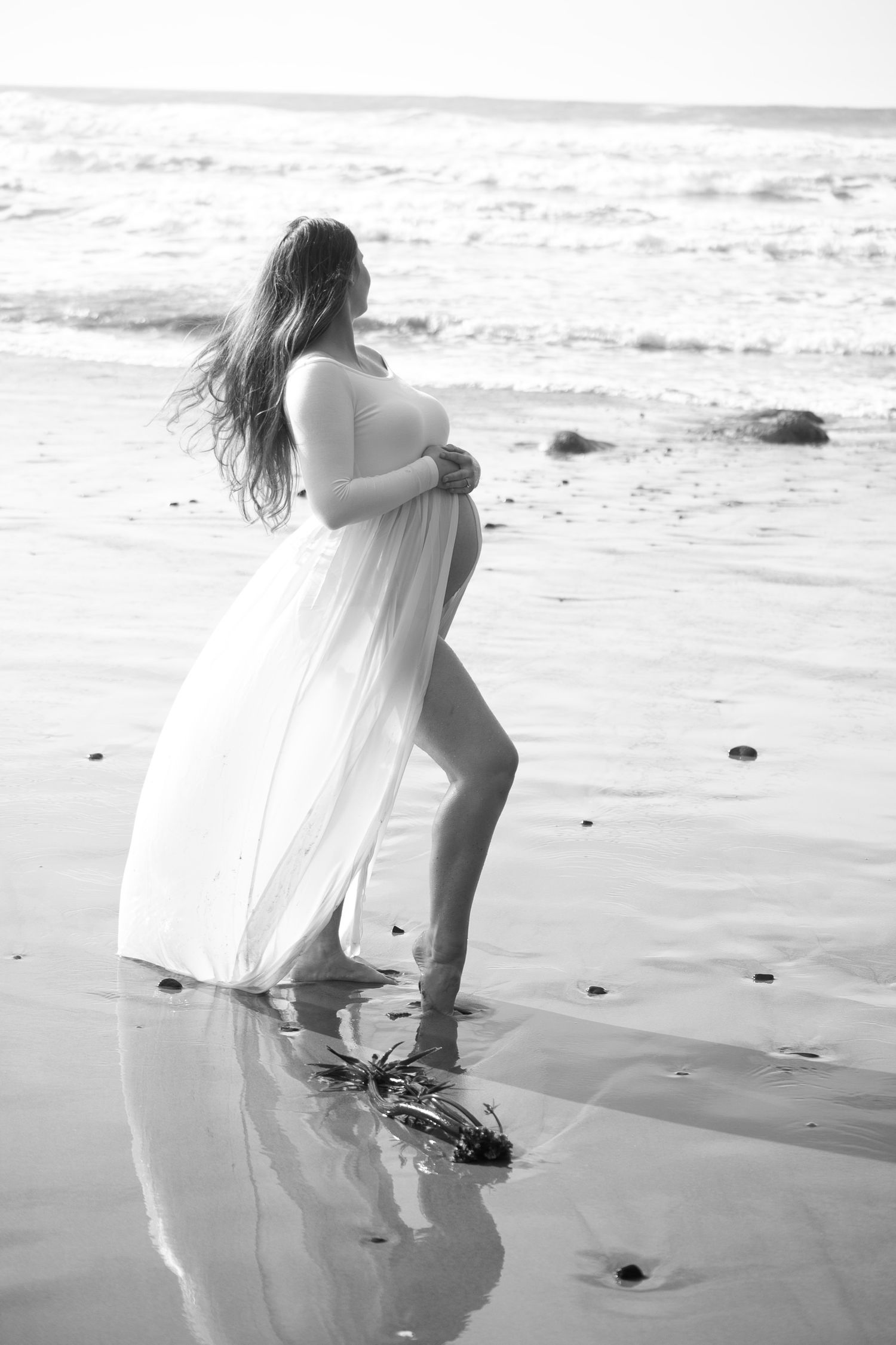 black and white photo of pregnant woman on the beach