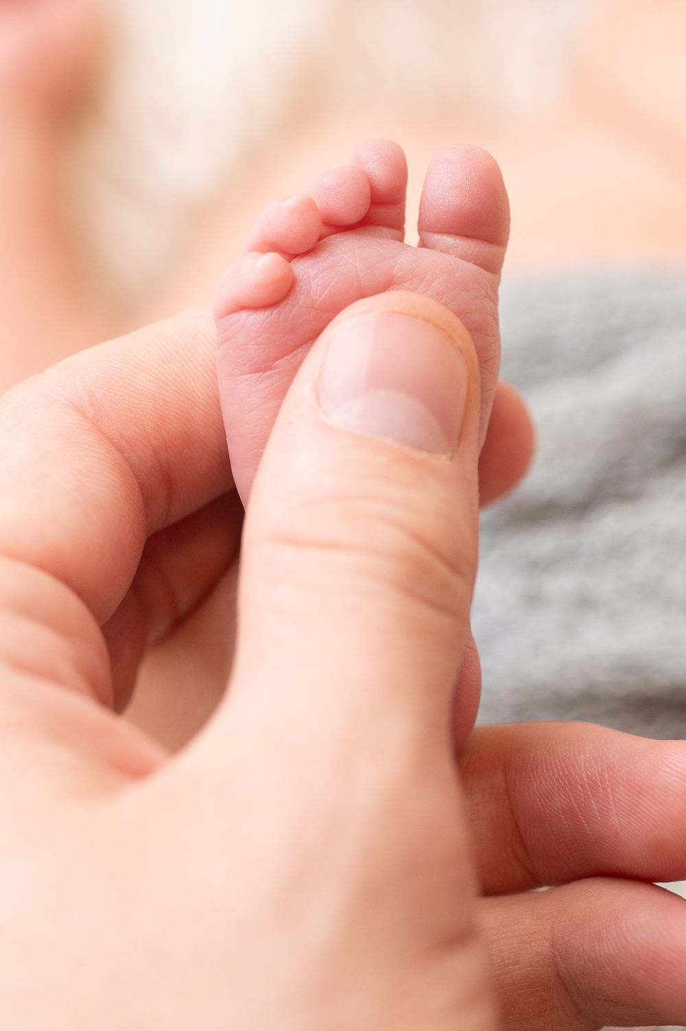 Close-up of a preemie baby’s foot against parent’s thumb, newborn photography session near Ashford, Kent.