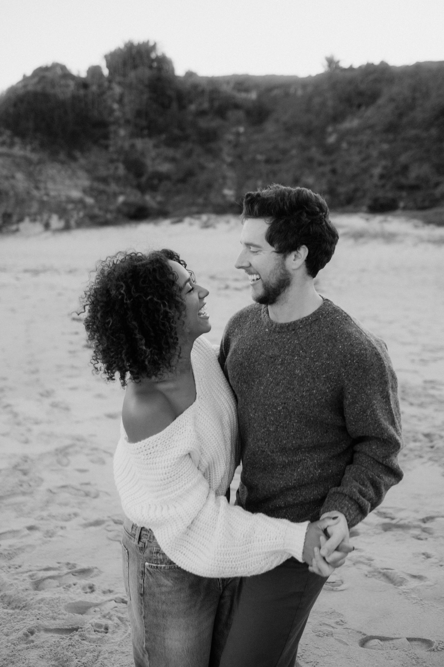 Dancing couple on a sandy beach with bushland behind them.