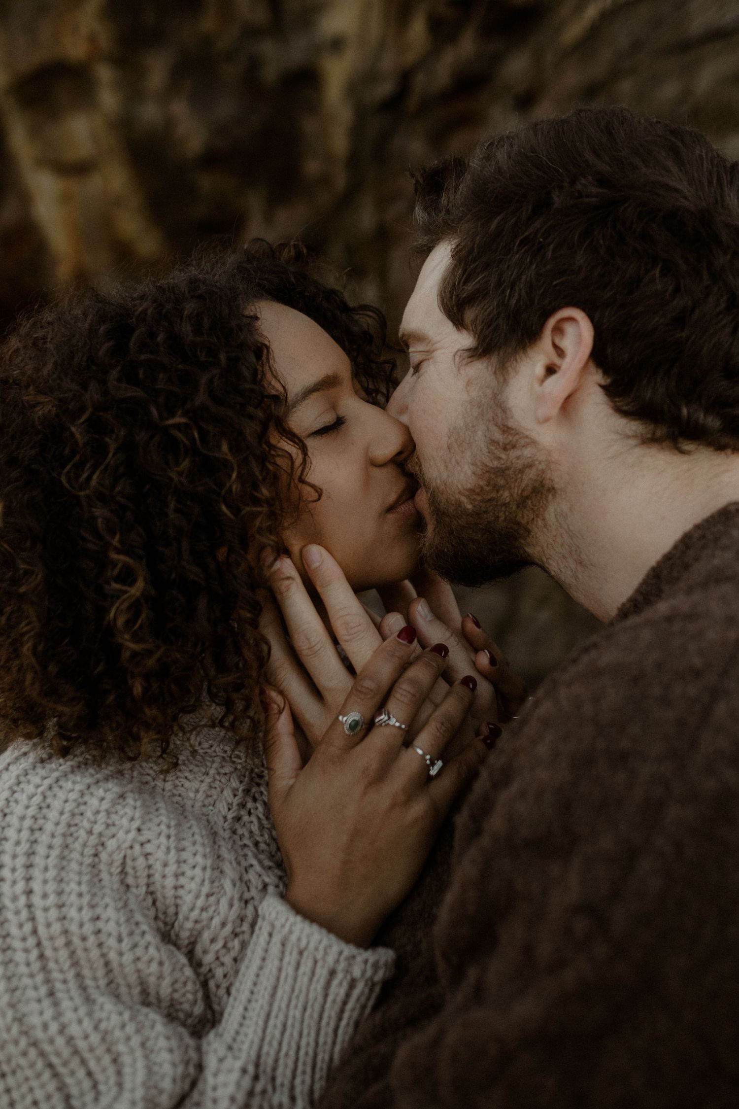 Couple kissing gently and holding each other's faces.