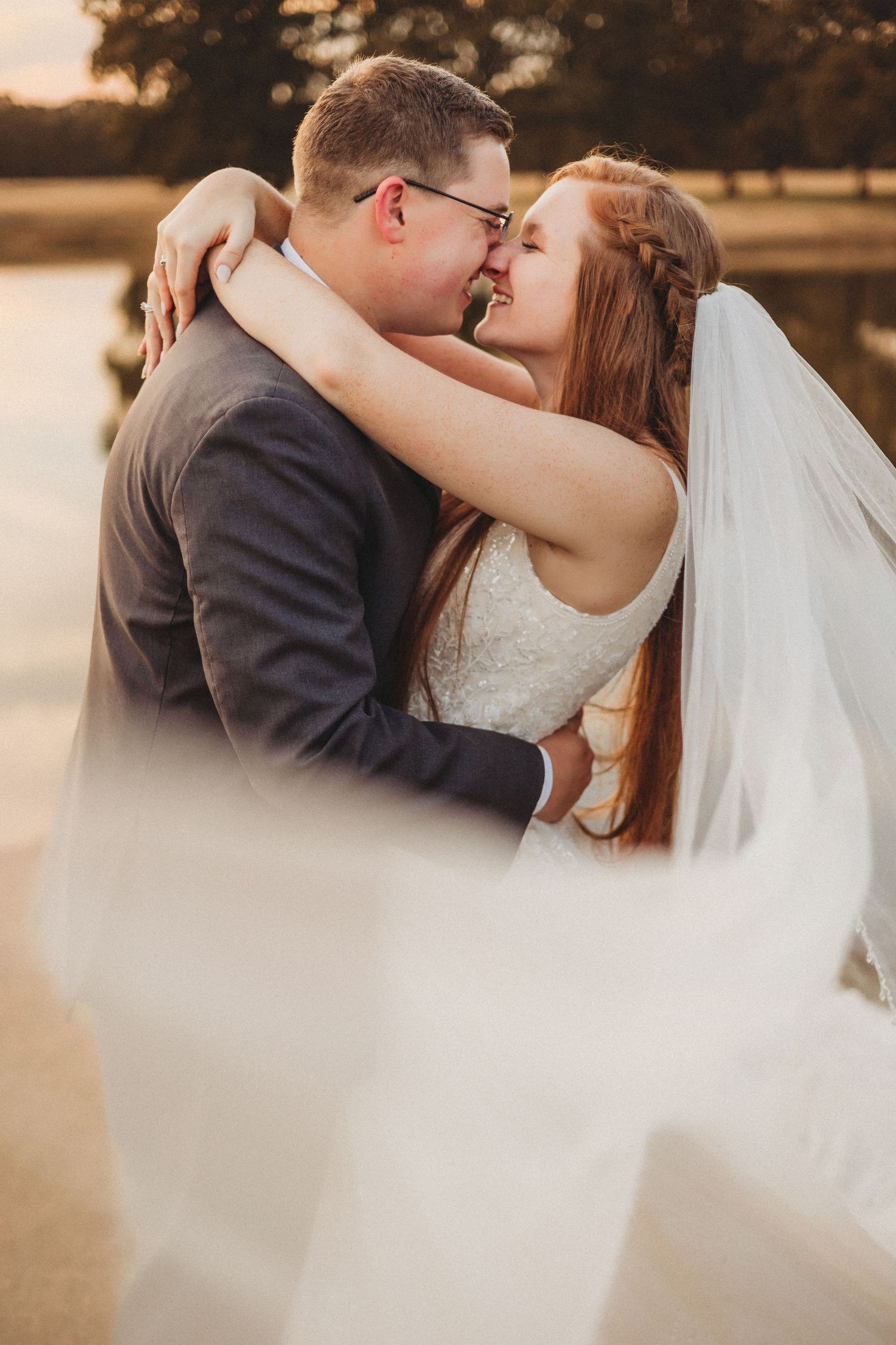 Romantic sunset wedding portrait with bride's veil flowing in the breeze.