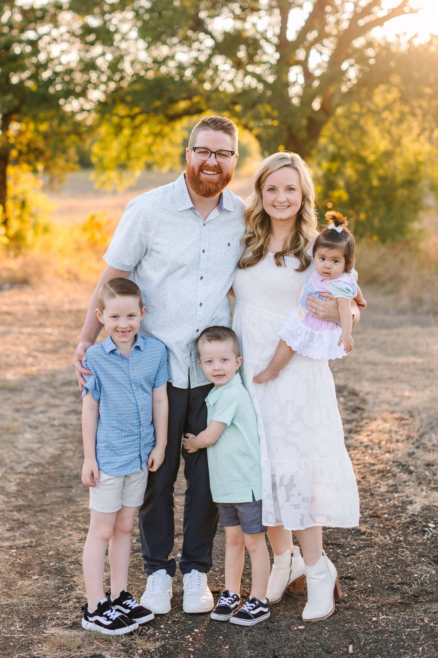 Sunset portrait of a group in coordinating blue and white outfits against a natural backdrop.