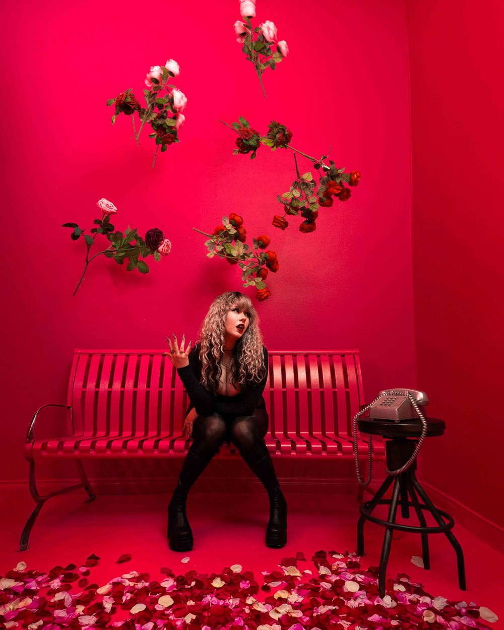 Model poses in red lighting with a vintage rotary phone for a stylized horror shoot, captured by Chris Cornish Photography.
