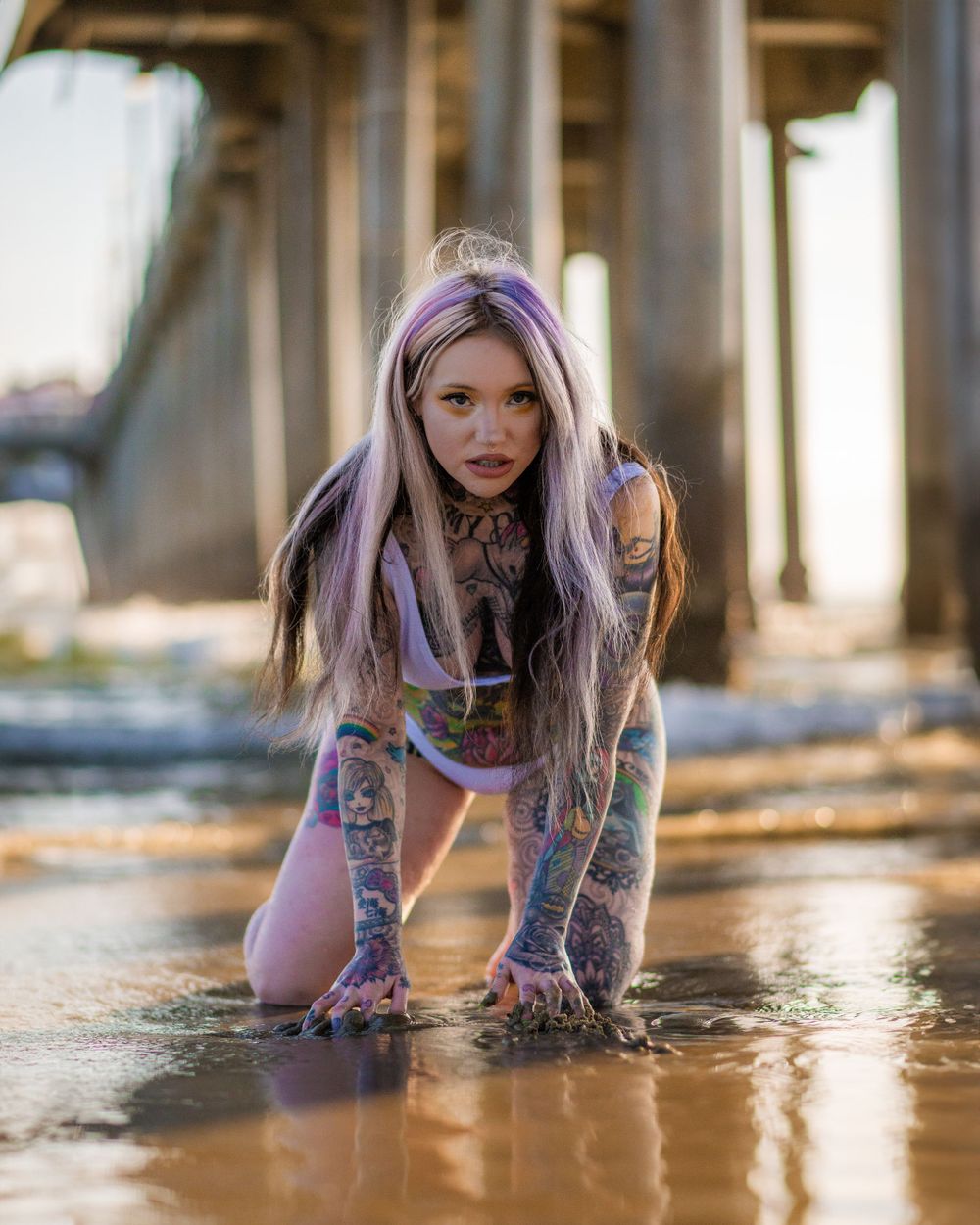 Heavily tattooed female model in a bikini posing under the Huntington Beach Pier