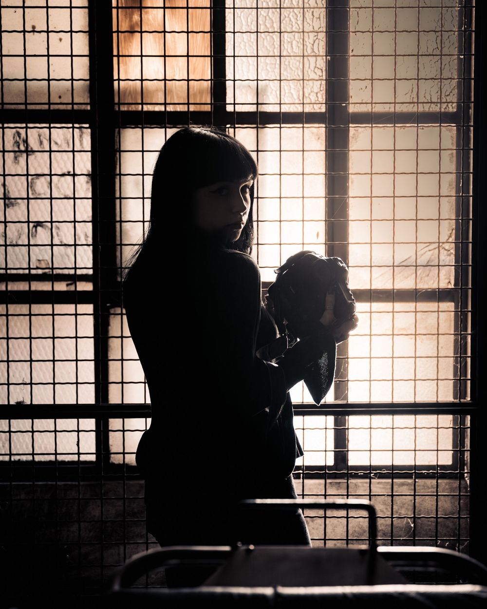 a backlit photo of a female model holding a camera