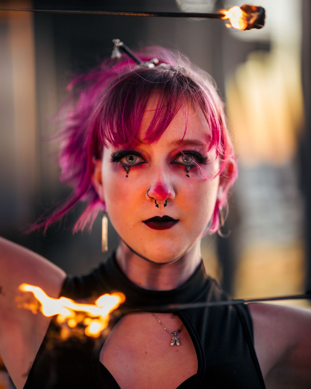 Female fire performer on the beach below Huntington Beach Pier, holding flaming sticks