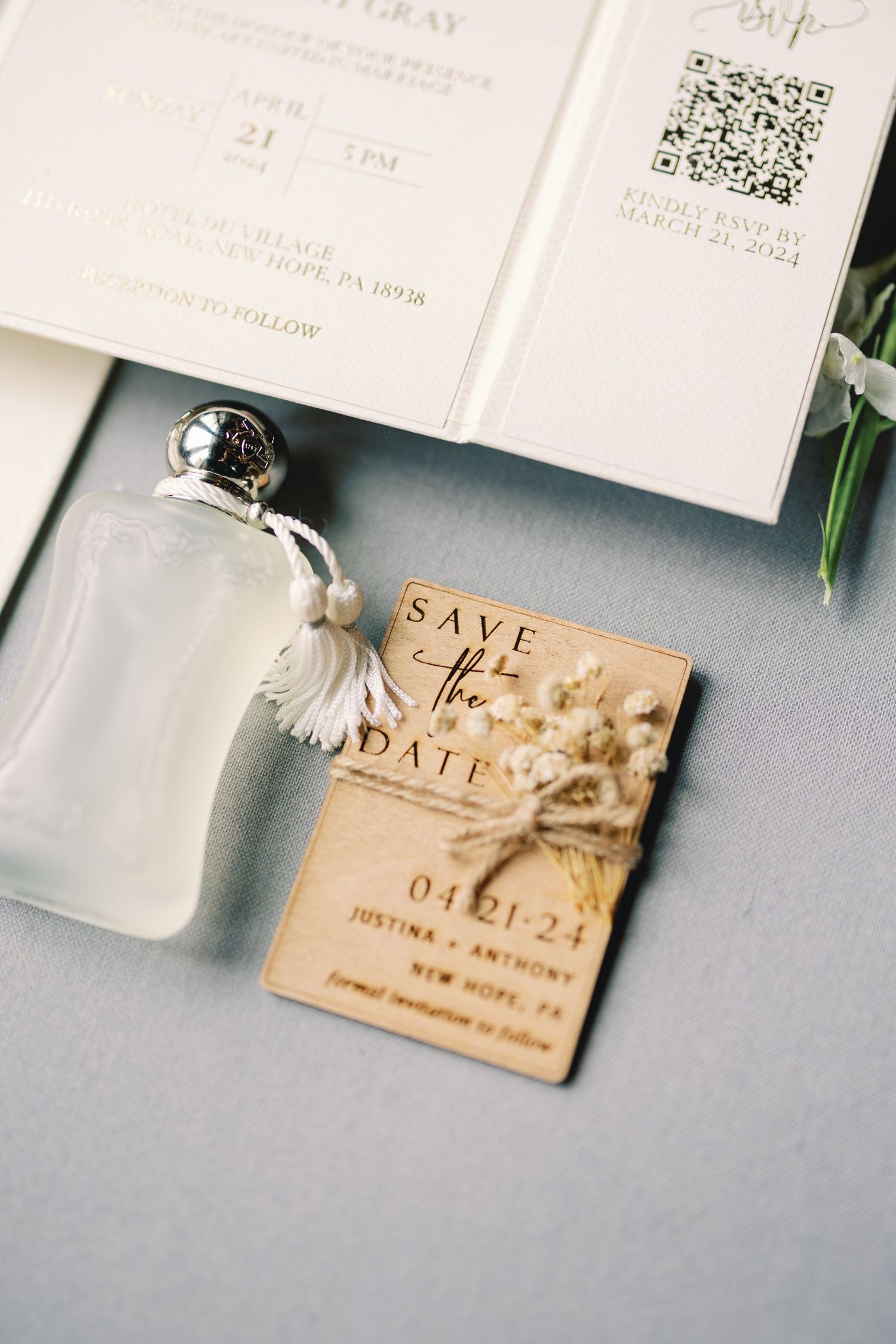Wooden save the date card for Justina and Anthony, New Hope PA, beside perfume bottle and wedding invitation suite.
