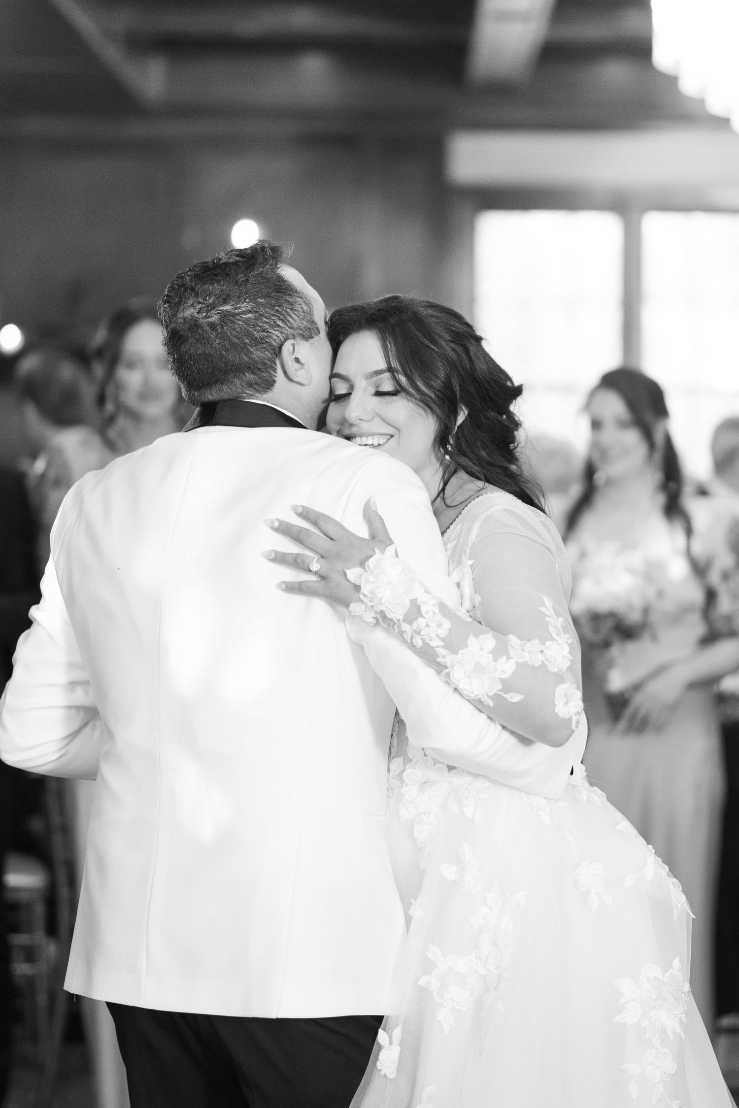 Black and white photo of bride and groom sharing emotional first dance at wedding reception.