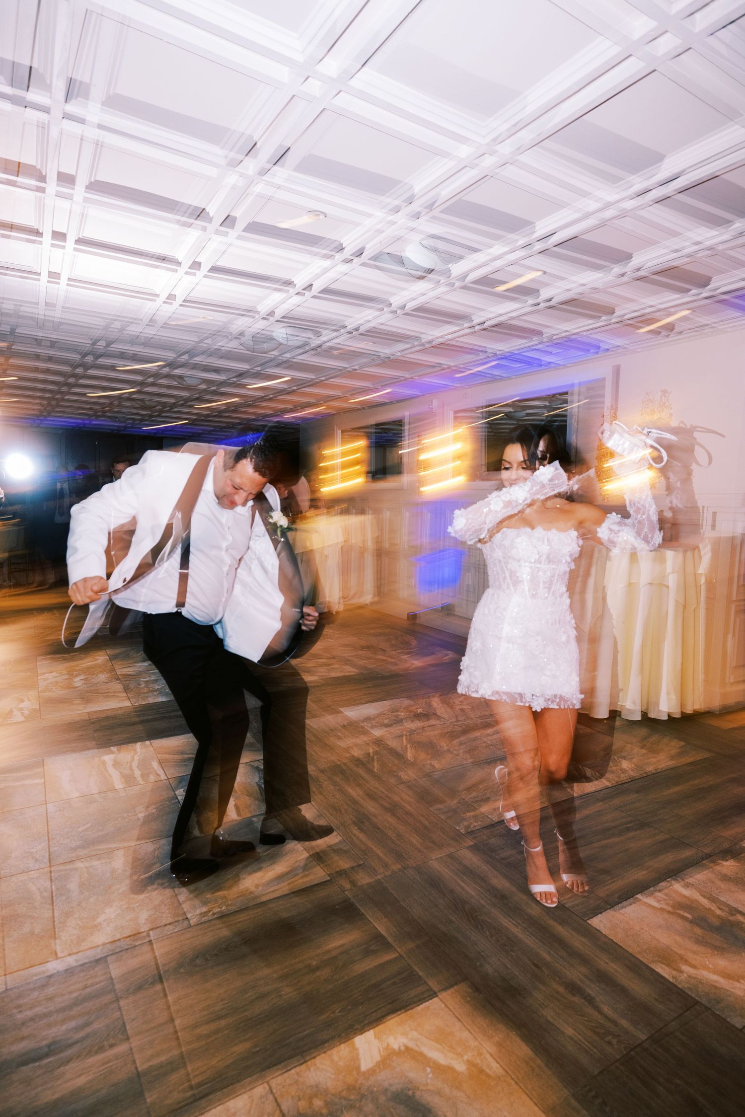 Bride and groom dance energetically on the dance floor at their wedding reception.