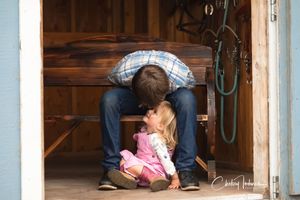Candid portrait of a young boy sharing a quiet moment with his little sister inside a rustic barn, captured by a family photographer