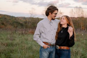 Couple sharing intimate moment in field during golden hour.