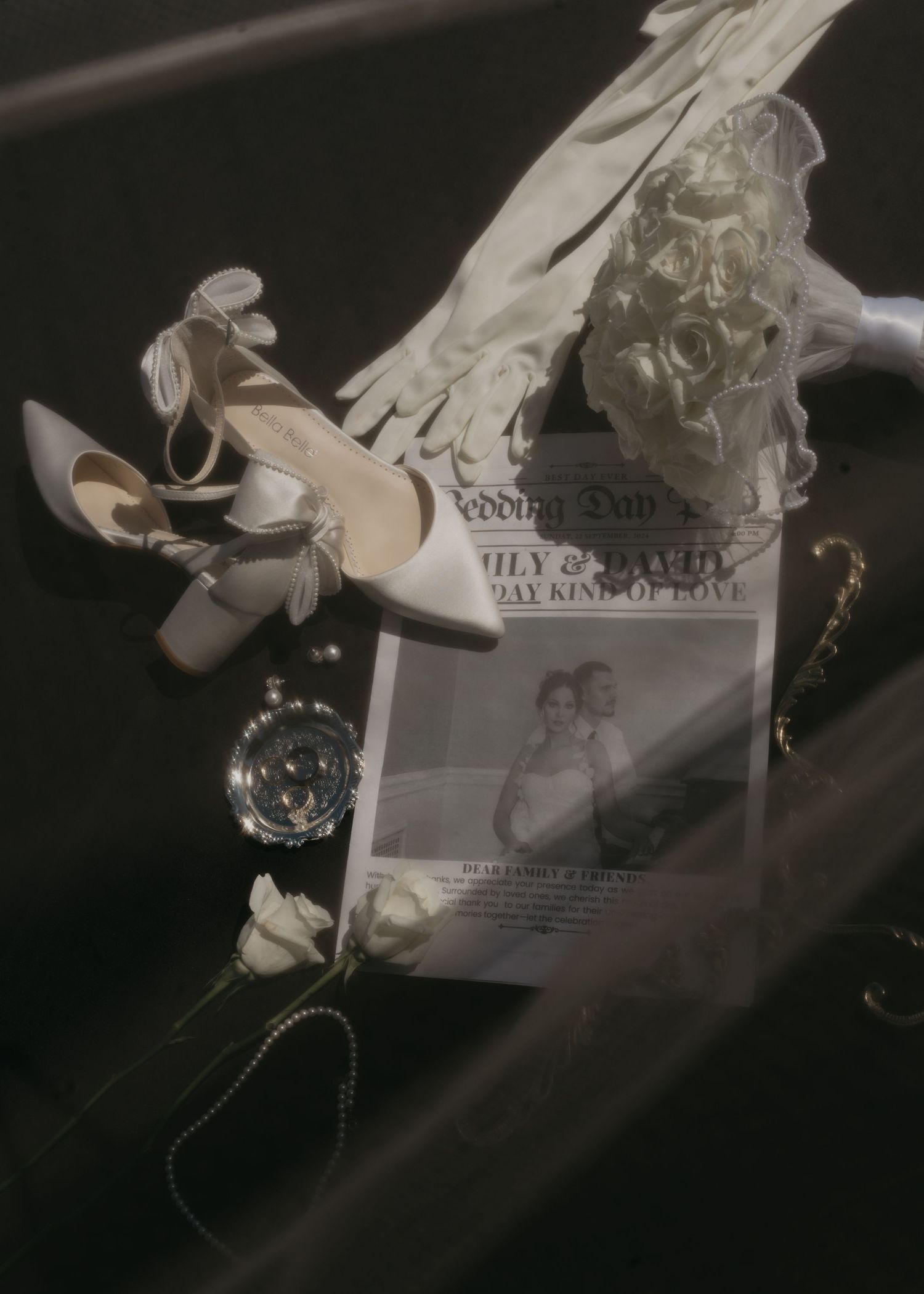 Wedding details arranged artistically including bridal shoes, jewelry, and a photo invitation in black and white.