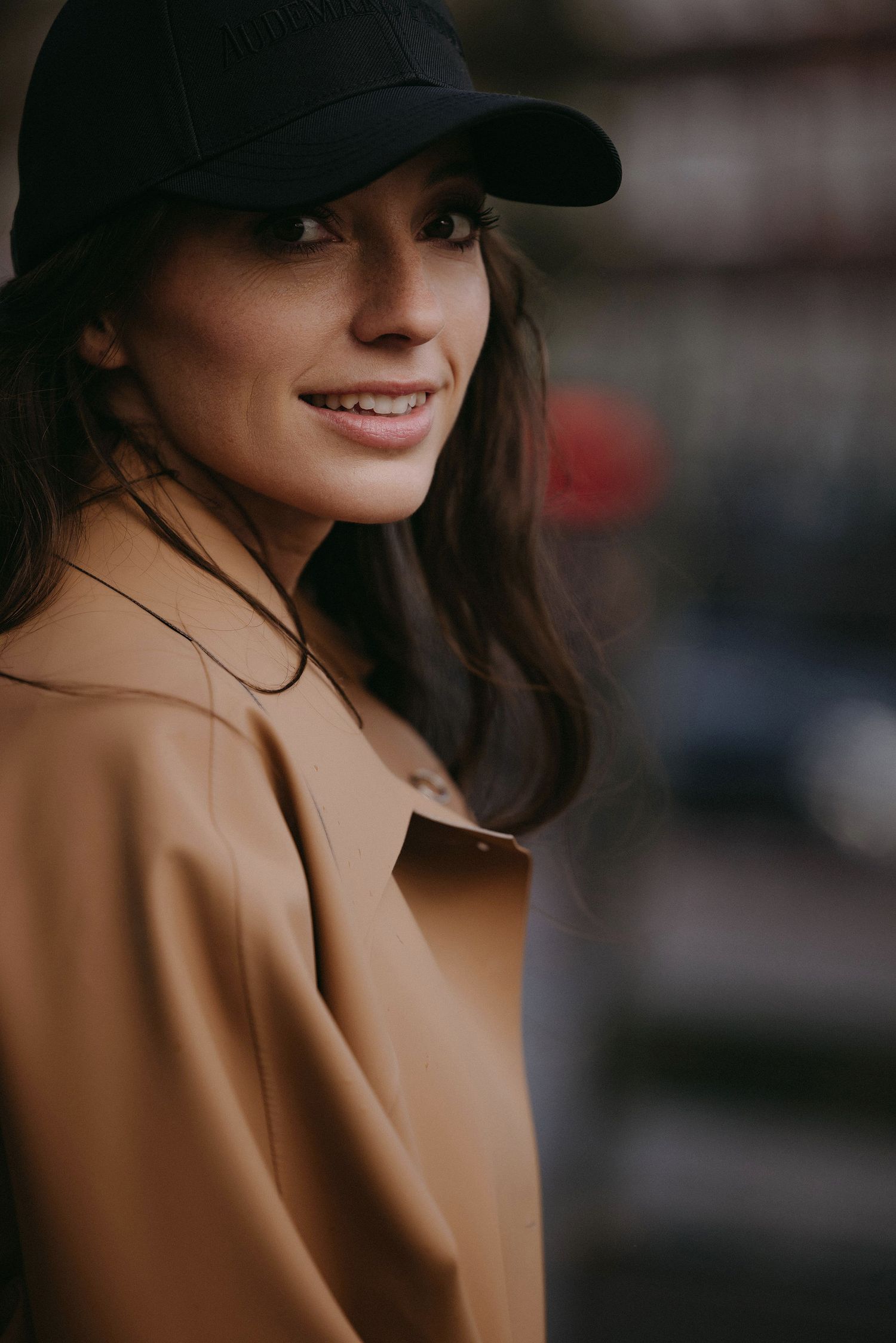 Urban style portrait with black baseball cap and camel coat.