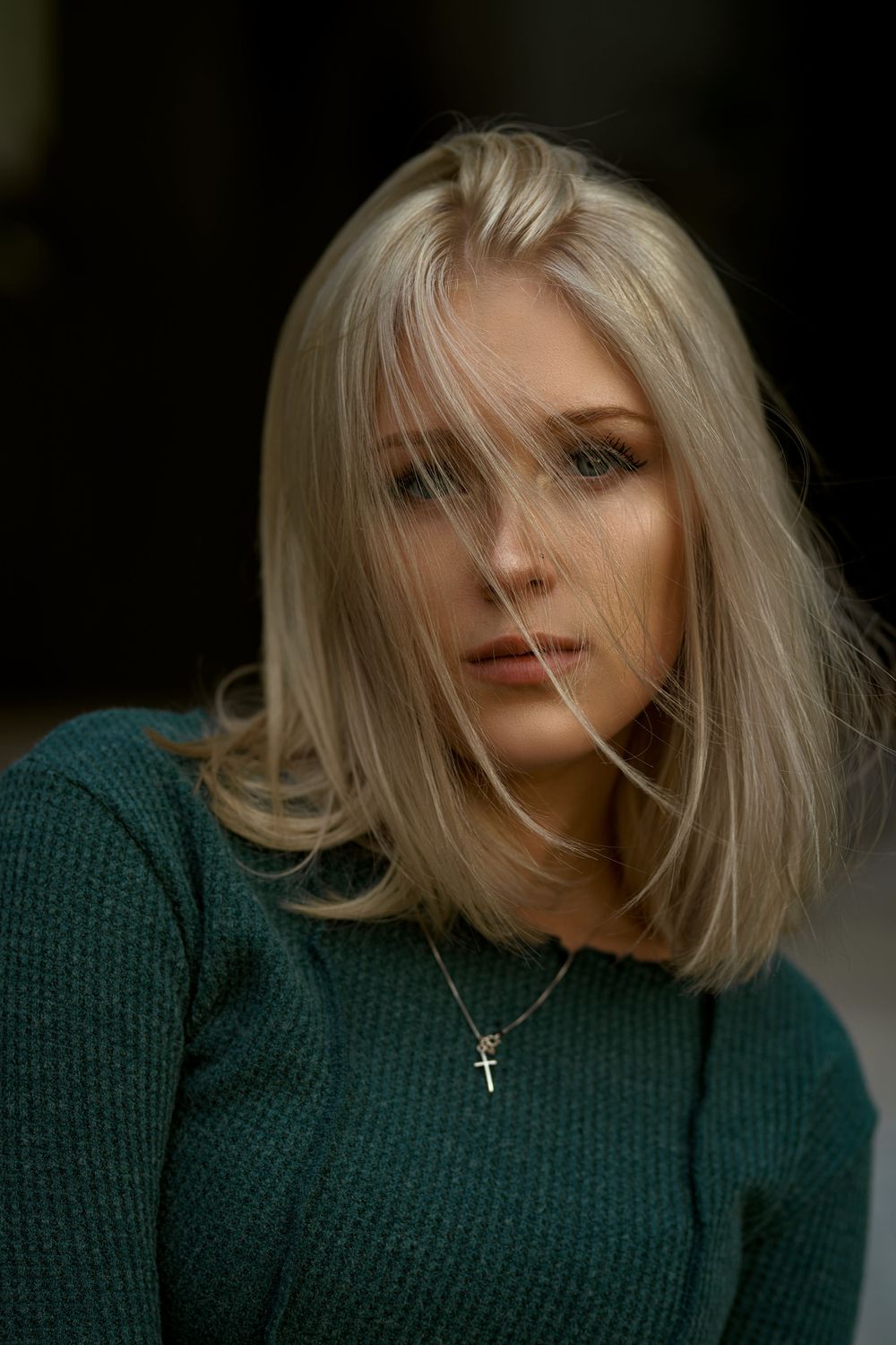 Moody portrait sequence in dark green knit sweater against black background.