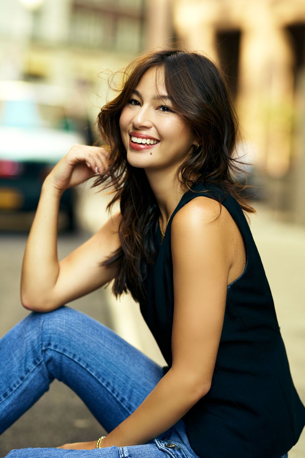 Casual fashion series in black tank top and blue jeans against urban backdrop.