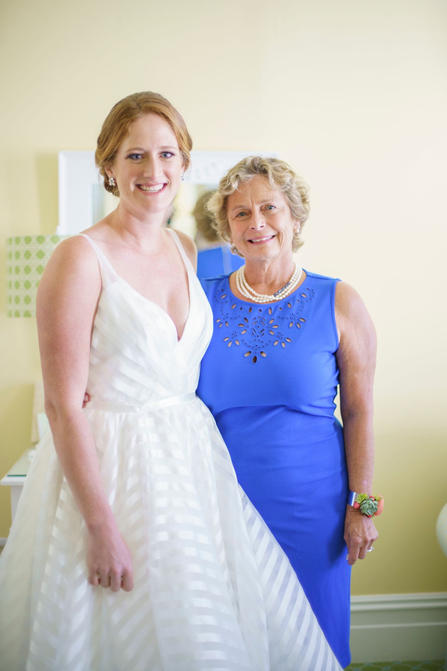 Bride in white V-neck gown poses with older woman in royal blue dress. Gasparilla Inn