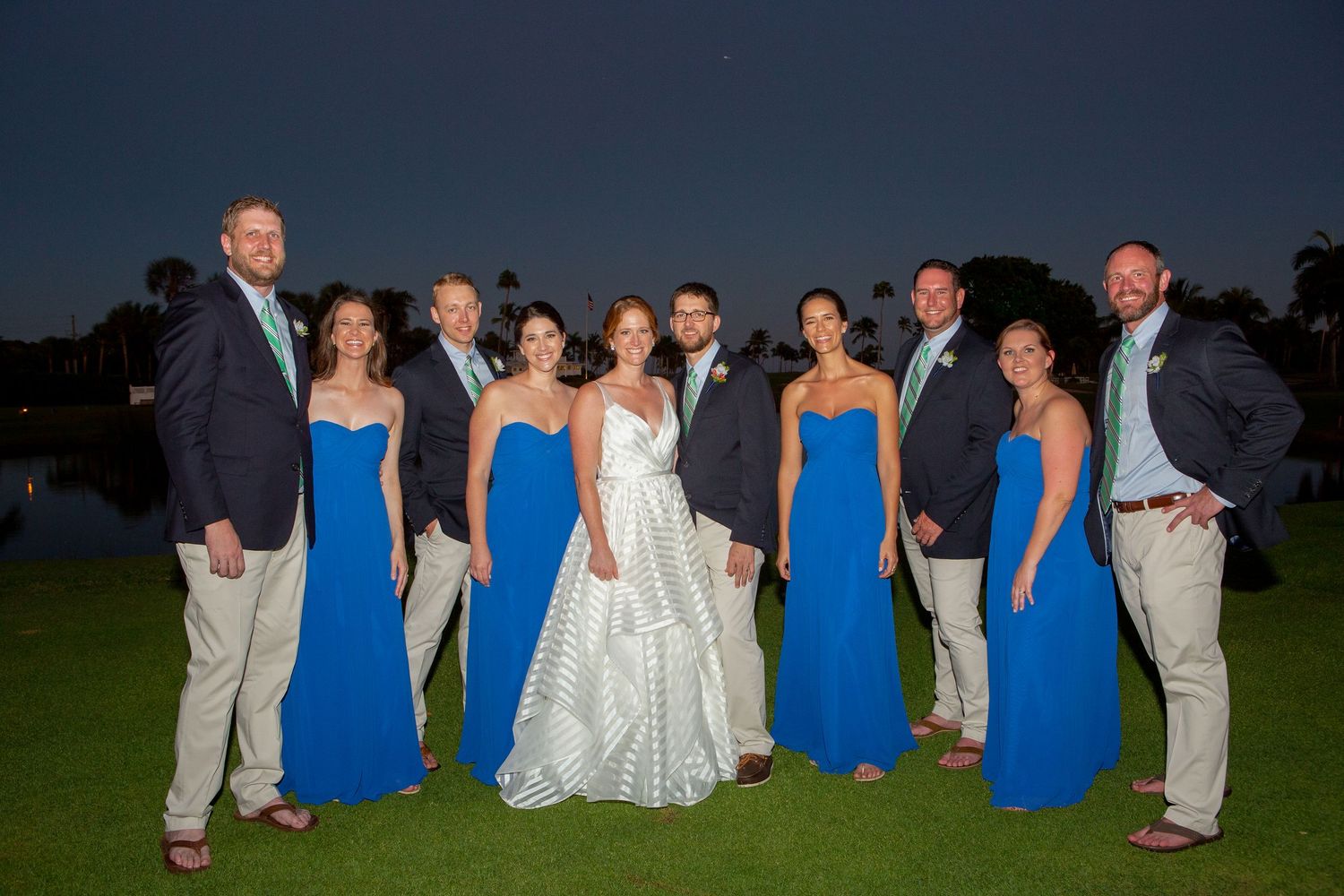 Wedding party poses outdoors at dusk in blue bridesmaid dresses and navy suits. Gasparilla Inn