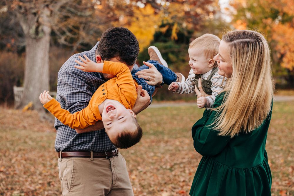 A joyful outdoor autumn photoshoot with warm golden sunlight filtering through trees.