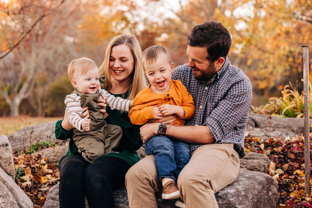 Candid moments captured during a fall family session with vibrant orange foliage in the background.