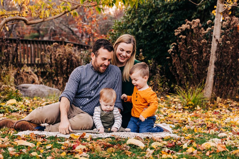 Family enjoying quality time together among fallen autumn leaves.