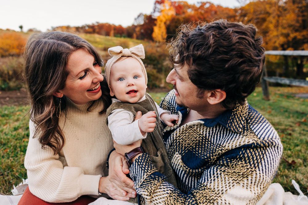 Joyful family moment captured during autumn photoshoot with fall foliage in the background.