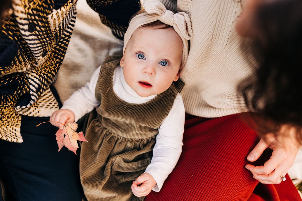 Close-up portrait of a baby wearing white against an autumn backdrop.