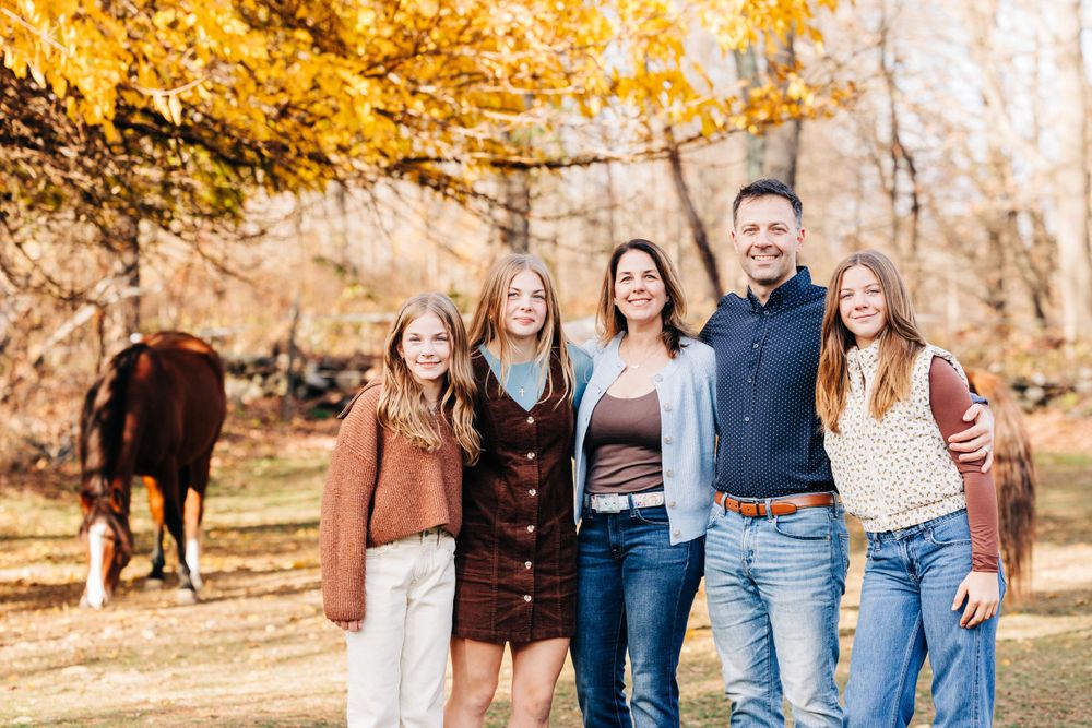 People in casual attire posing together outdoors during golden hour with autumn colors.
