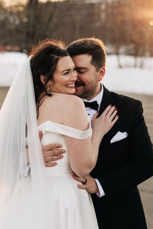 Romantic wedding portrait at sunset showing intimate moment between couple in formal attire and flowing white veil.