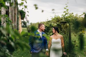 A couple walks through a lush vineyard on their wedding day.