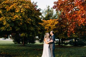 A couple embraces under vibrant fall foliage during their wedding photoshoot.
