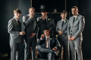 A group of men in gray suits and formal attire pose together in a stylish formal portrait setting.