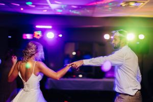 A romantic dance moment captured under purple and green reception lighting.