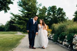 A couple walking together on a stone path surrounded by manicured garden landscaping.