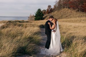 A romantic moment captured in tall grass with rolling hills and autumn trees in the background.