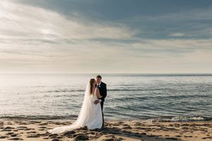 Silhouetted couple standing together on a beach during golden hour with ocean waves.