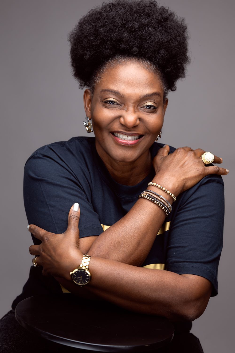 Studio portrait showing a joyful expression and stylish jewelry against dark background.