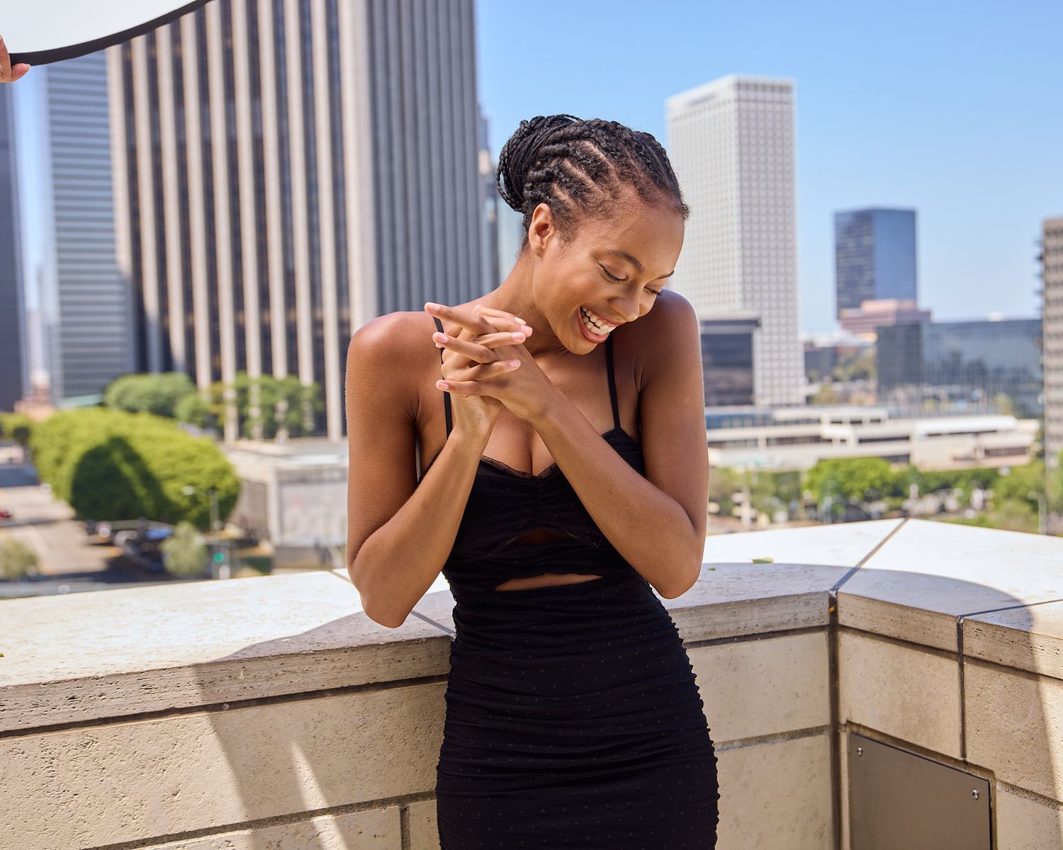 Joyful rooftop portrait in black dress against urban skyline, at Disney Music Hall LA