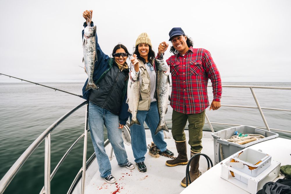 A group of friends enjoying a boat trip together, standing on the deck of a sailboat against a misty seascape.