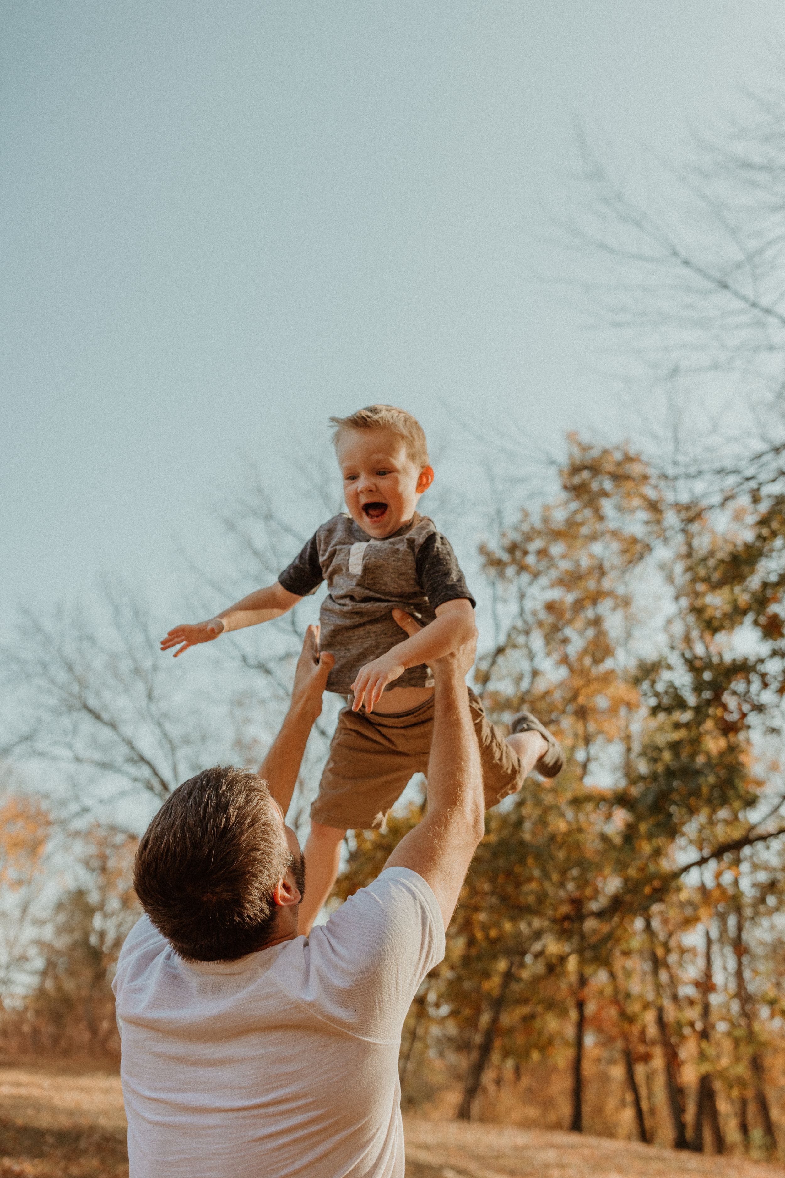 A joyful moment captured as a child is lifted high into the autumn air.