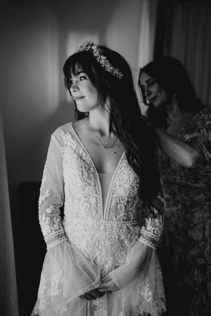 Bride in delicate lace wedding dress poses elegantly in black and white portrait series.